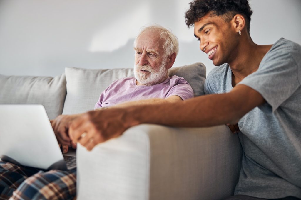 Aged man and his caregiver surfing the Internet