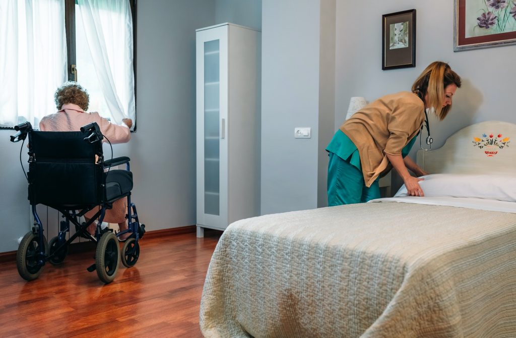 Caregiver making the bed of an elderly patient